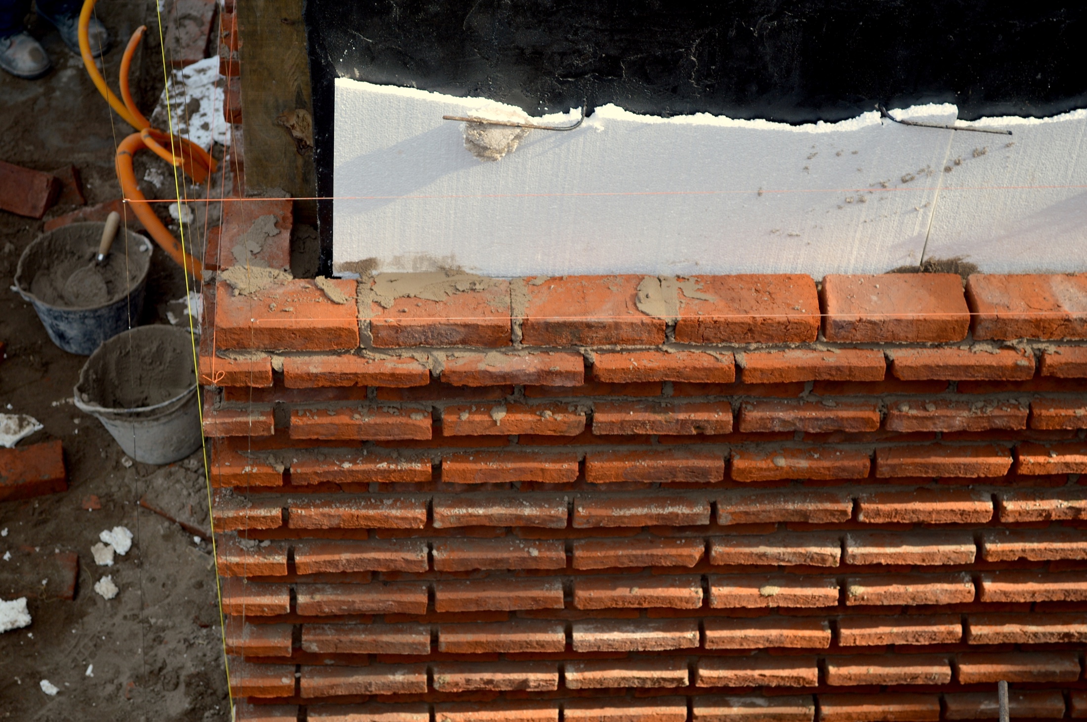 Hilos de replanteo y capas constructivas en una fachada