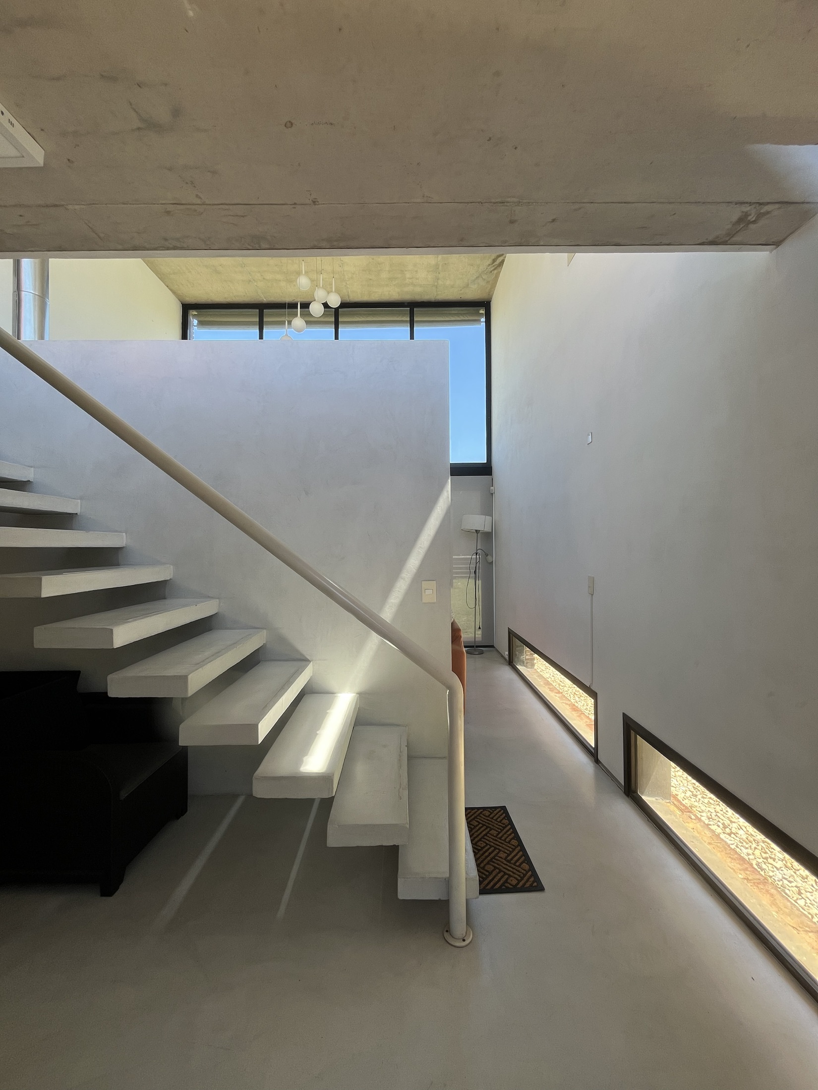 Escalera y espacio social de Casa I iluminados desde lo alto