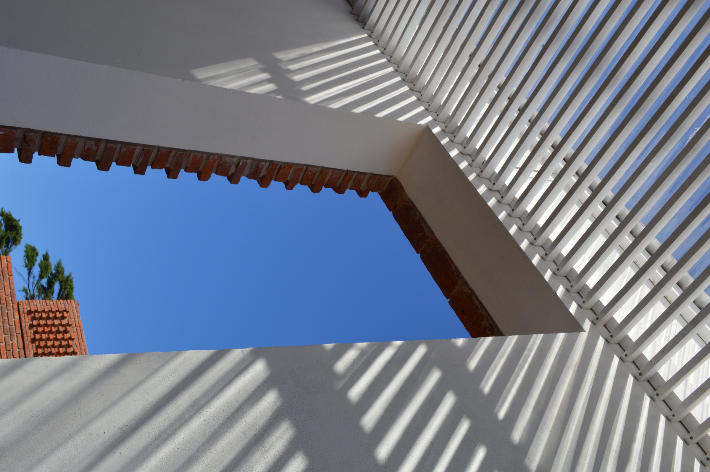 Pérgola y umbral de Casa A recortados por sombras lineales